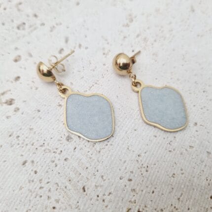 Ατσάλινο κρεμαστό σκουλαρίκι με ακανόνιστο στοιχείο με άσπρο σμάλτο με χρυσόσκονη